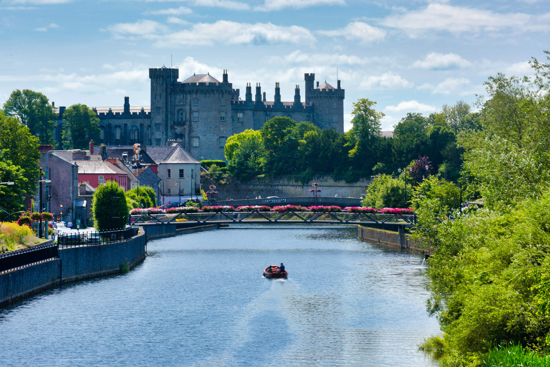 small boat on a wide river leading up to a Large castle