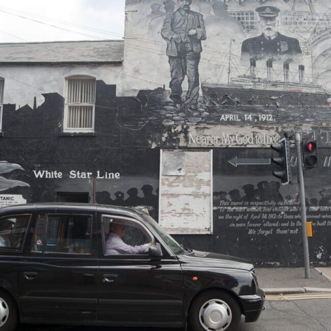 a black london taxi cab with a black and white mural in the backgroung